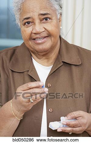 Stock Photograph - Senior African American woman holding medication. Fotosearch
