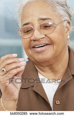 Senior African American woman looking at pill View Large Photo Image Stock Photography - Senior African American woman looking at pill. Fotosearch