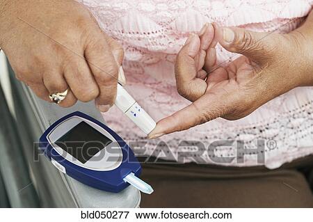 Stock Photo - Senior African American woman testing blood sugar. Fotosearch