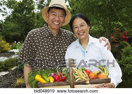 Stock Photo - Senior Asian couple with basket of vegetables. Fotosearch