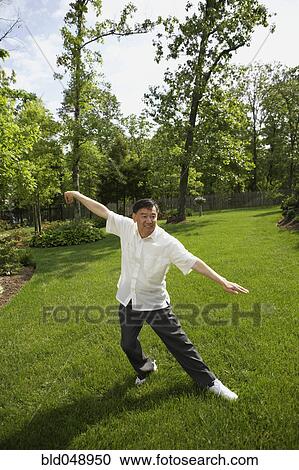 Stock Image - Senior Asian man practicing tai chi. Fotosearch
