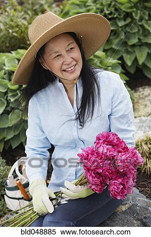 Senior Asian woman holding flowers View Large Photo Image Stock Photography - Senior Asian woman holding flowers. Fotosearch