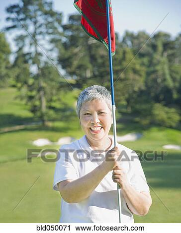 Senior Asian woman holding golf flag View Large Photo Image Stock Image - Senior Asian woman holding golf flag. Fotosearch