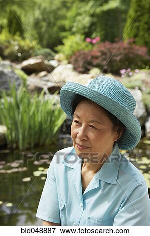 Stock Photo - Senior Asian woman next to pond. Fotosearch
