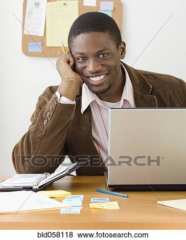 Stock Photo - African businessman sitting at desk. Fotosearch