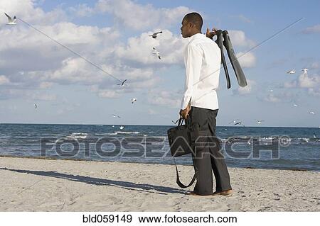 Stock Photo - African businessman standing on beach. Fotosearch