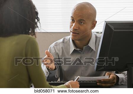 Stock Image - African businessman talking to co-worker. Fotosearch