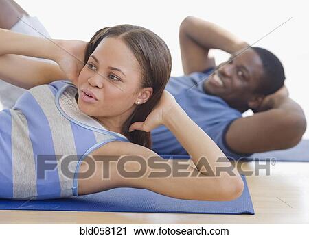 Stock Image - African couple exercising on mats. Fotosearch