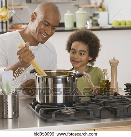 Stock Photograph - African father and son making pasta. Fotosearch