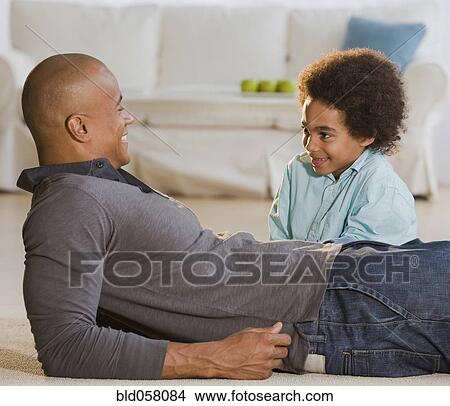 Picture - African father and son smiling at each other. Fotosearch