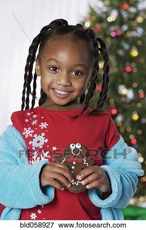 Stock Photo - African girl holding Christmas cookie. Fotosearch