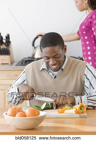Stock Photography - African man chopping vegetables. Fotosearch