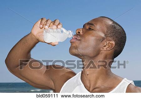Stock Image - African man drinking water bottle. Fotosearch