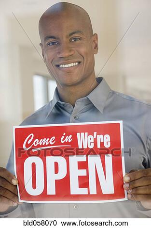 Stock Image - African man holding Open sign. Fotosearch