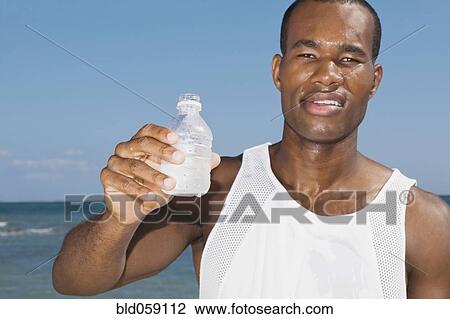 African man holding water bottle View Large Photo Image Stock Image - African man holding water bottle. Fotosearch