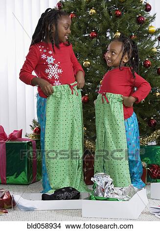 Picture - African sisters holding matching Christmas gifts. Fotosearch