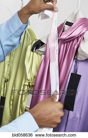 Stock Photograph - African woman holding fabric swatch against dress. Fotosearch