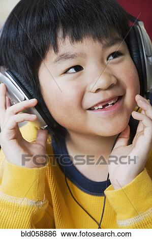 Stock Photograph - Asian boy listening to headphones. Fotosearch