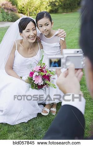 Stock Photography - Asian bride and flower girl having photograph taken. Fotosearch
