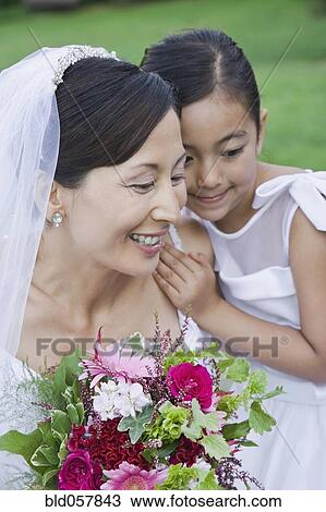 Stock Image - Asian bride and flower girl hugging. Fotosearch