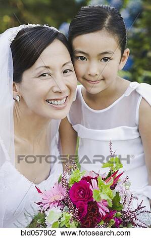 Stock Image - Asian bride and flower girl hugging. Fotosearch