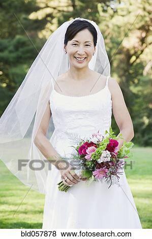 Asian bride holding bouquet View Large Photo Image Stock Photo - Asian bride holding bouquet. Fotosearch