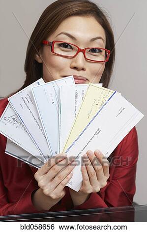 Stock Photograph - Asian businesswoman holding checks. Fotosearch