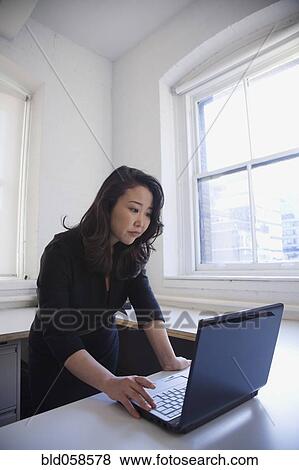 Asian businesswoman looking at laptop View Large Photo Image Stock Photo - Asian businesswoman looking at laptop. Fotosearch