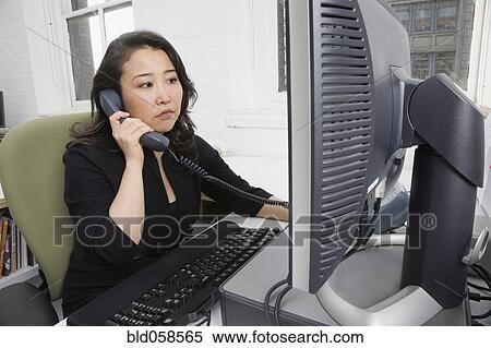 Stock Photography - Asian businesswoman talking on telephone. Fotosearch