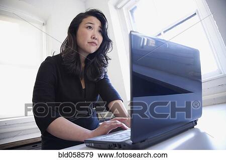 Asian businesswoman typing on laptop View Large Photo Image Stock Photo - Asian businesswoman typing on laptop. Fotosearch