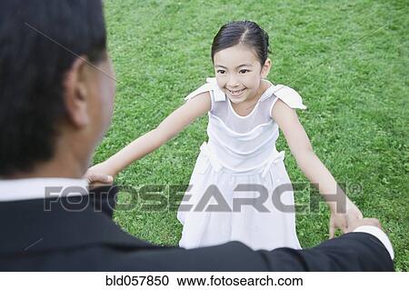 Stock Image - Asian father and daughter holding hands. Fotosearch