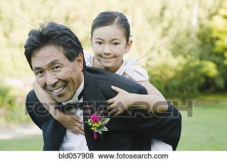 Stock Photo - Asian father giving daughter piggy back ride. Fotosearch