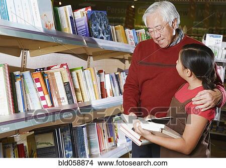 Asian grandfather and granddaughter reading in store View Large Photo Image Picture - Asian grandfather and granddaughter reading in store. Fotosearch