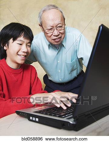 Asian grandfather and grandson looking at laptop View Large Photo Image Stock Photograph - Asian grandfather and grandson looking at laptop. Fotosearch