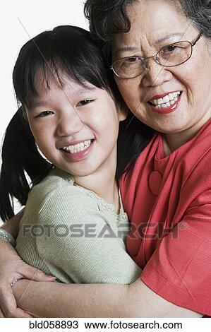 Stock Image - Asian grandmother and granddaughter hugging. Fotosearch
