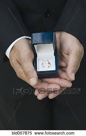 Stock Photography - Asian man holding engagement ring. Fotosearch