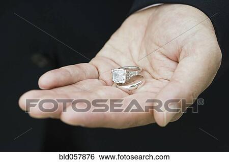 Stock Photograph - Asian man holding wedding rings. Fotosearch