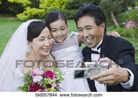 Asian newlyweds and daughter taking own photograph View Large Photo Image Picture - Asian newlyweds and daughter taking own photograph. Fotosearch