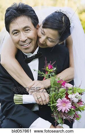 Stock Image - Asian newlyweds hugging. Fotosearch