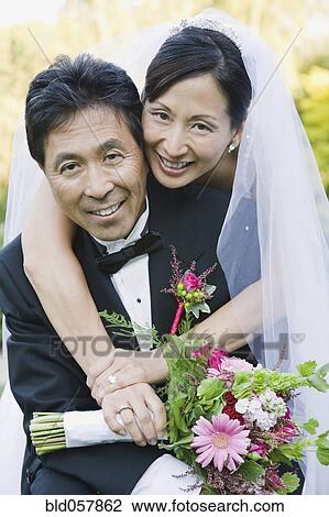 Stock Image - Asian newlyweds hugging. Fotosearch