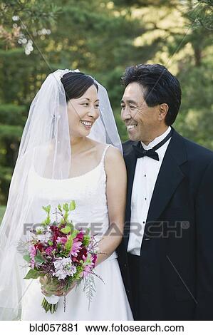 Stock Image - Asian newlyweds smiling at each other. Fotosearch