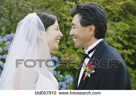 Stock Image - Asian newlyweds smiling at each other. Fotosearch
