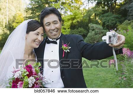 Stock Photograph - Asian newlyweds taking own photograph. Fotosearch