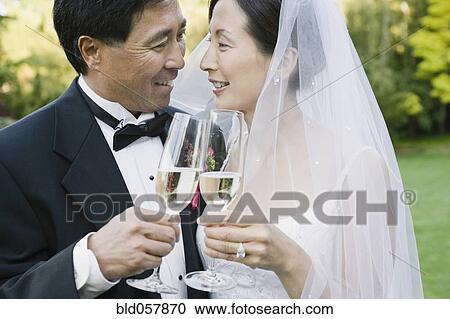 Stock Image - Asian newlyweds toasting with champagne. Fotosearch