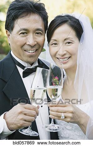 Asian newlyweds toasting with champagne View Large Photo Image Stock Photo - Asian newlyweds toasting with champagne. Fotosearch