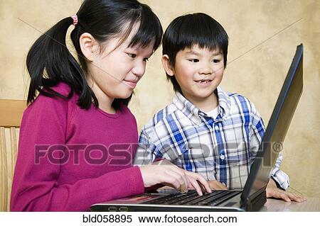 Asian siblings looking at laptop View Large Photo Image Stock Photography - Asian siblings looking at laptop. Fotosearch