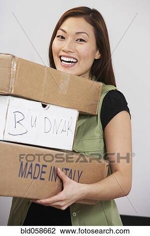 Stock Image - Asian woman carrying stack of packages. Fotosearch