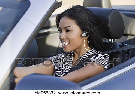 Stock Image - Asian woman driving convertible car. Fotosearch