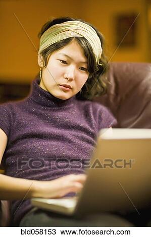 Stock Image - Asian woman looking at laptop. Fotosearch
