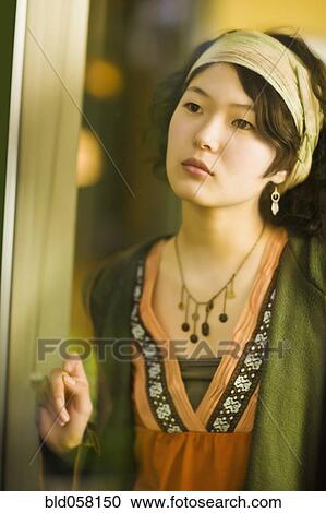 Stock Image - Asian woman looking out window. Fotosearch